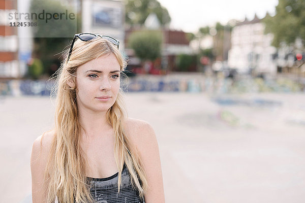 Porträt einer jungen Skateboarderin mit langen blonden Haaren im Skatepark