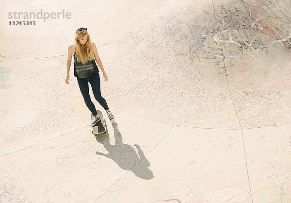 Hoher Winkel der jungen Skateboarderin beim Skateboarden im Skatepark