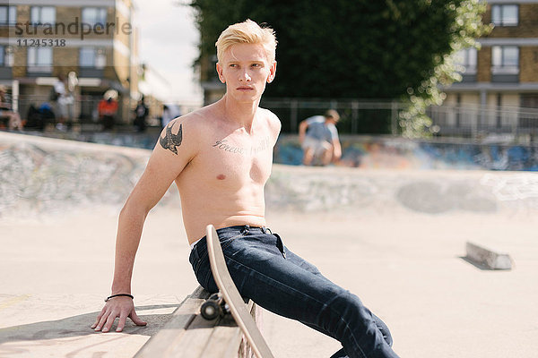 Junger männlicher Skateboarder schaut sich im Skatepark über die Schulter