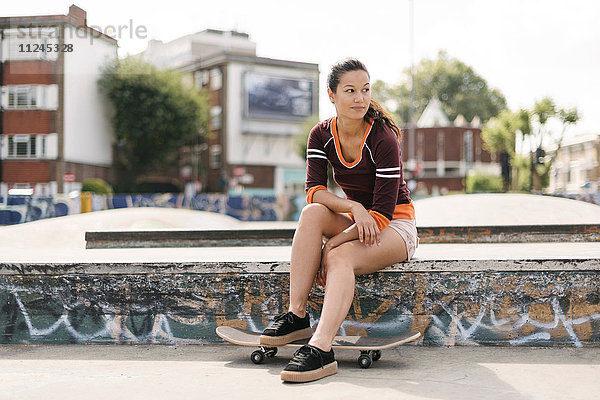 Skateboarderin sitzt im Skatepark