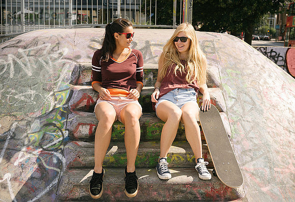 Zwei Skateboard-Freundinnen unterhalten sich im Skatepark
