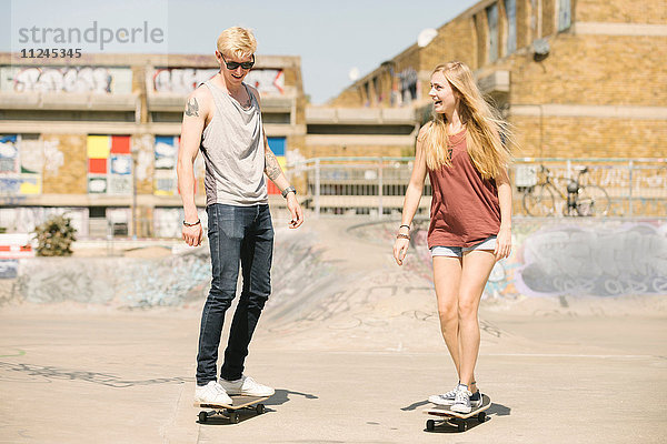 Junge Skateboardfreundinnen und -freunde skateboarden im Skatepark