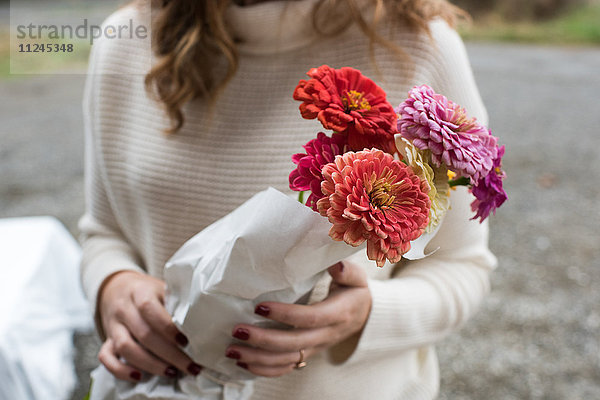 Mittlere Sektion einer Frau  die Blumensträuße im Bioladen hält