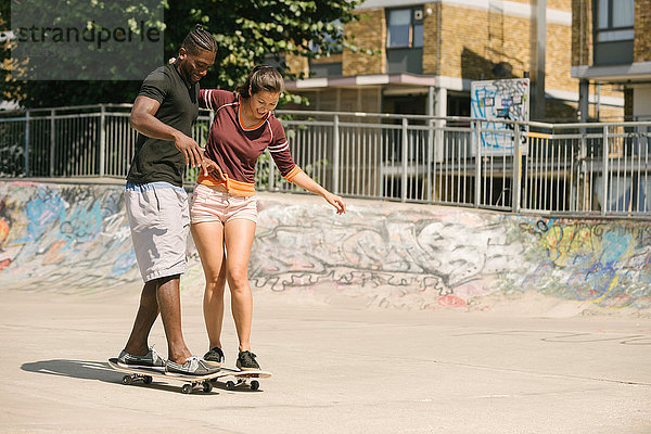 Junger Mann und Frau üben im Skatepark das Gleichgewicht auf dem Skateboard