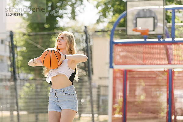 Junge Frau übt auf dem Basketballplatz