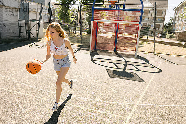Junge Frau läuft mit Ball auf Basketballfeld