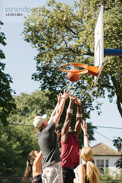 Basketballerinnen und Basketballer  die Bälle auf Basketballkörbe werfen