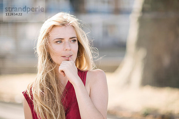 Bildnis einer hübschen jungen Frau mit langen blonden Haaren im Park