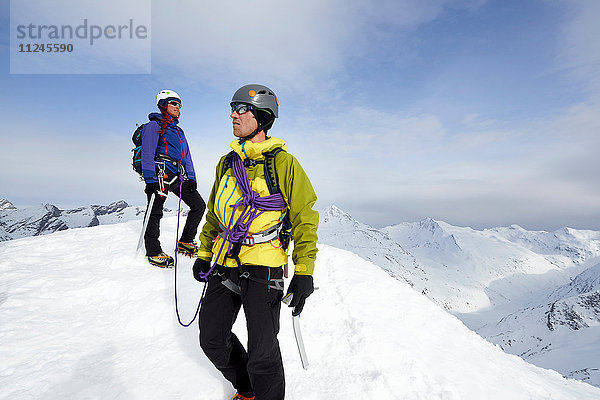 Bergsteiger auf dem Gipfel eines schneebedeckten Berges mit Blick in die Ferne  Saas Fee  Schweiz