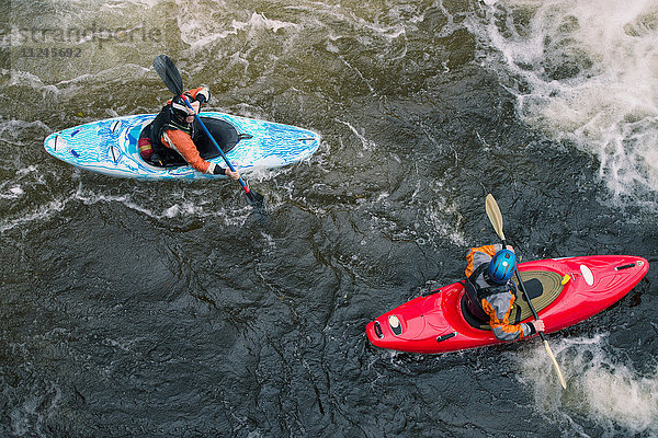 Draufsicht auf zwei Kajakfahrer  die in den Stromschnellen des River Dee paddeln