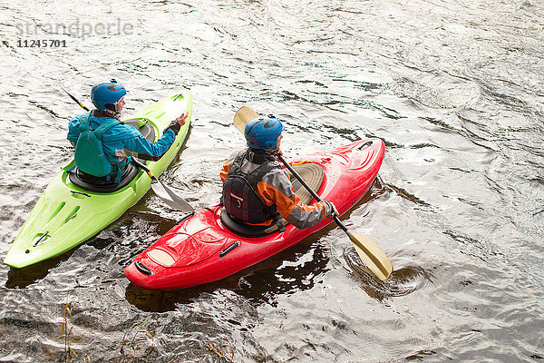 Männliche und weibliche Kajakfahrer paddeln auf dem River Dee