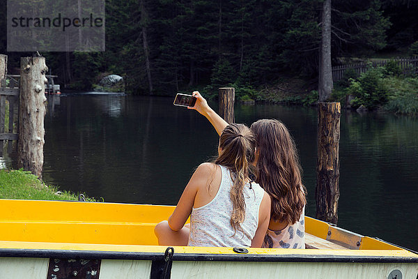 Zwei junge Freundinnen beim Smartphone-Selfie im Ruderboot  Sattelbergalm  Tirol  Österreich