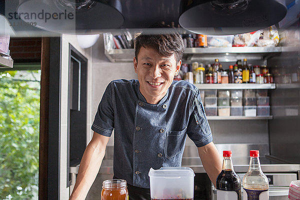 Porträt eines Küchenchefs in einer Großküche  der lächelnd in die Kamera schaut