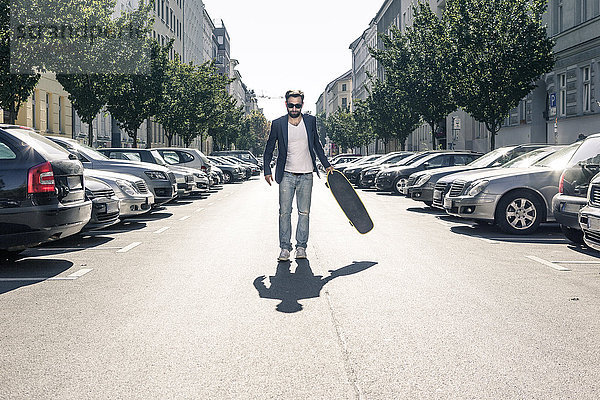 Mann hält Skateboard auf der Straße  Berlin  Deutschland