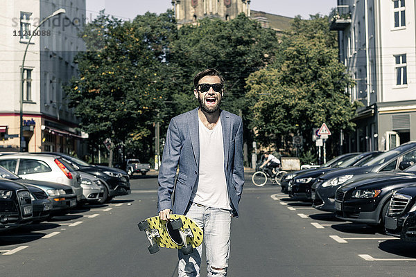 Mann hält Skateboard auf der Straße  Berlin  Deutschland