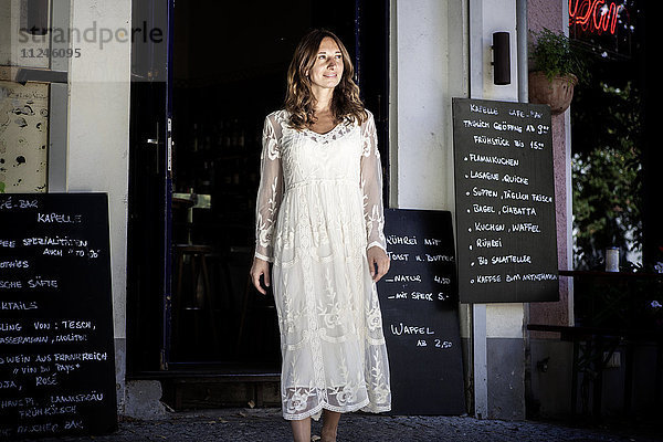 Frau in der Tür eines Cafés  die lächelnd wegschaut  Berlin  Deutschland