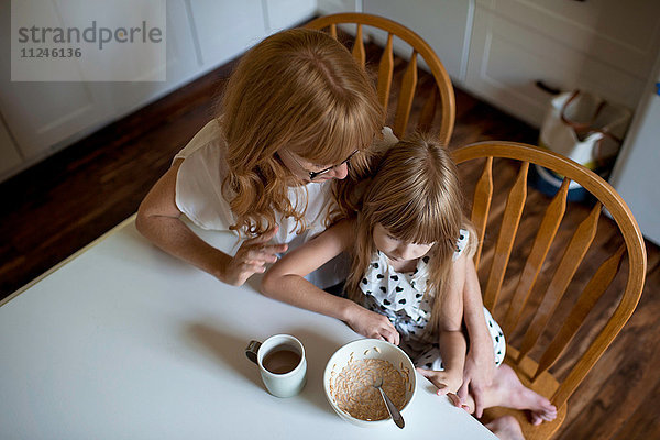 Mutter und Tochter kuscheln am Frühstückstisch