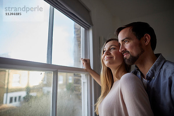 Mittleres erwachsenes Paar mit Blick durchs Schlafzimmerfenster