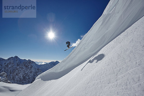Männlicher Freestyle-Skifahrer springt in der Luft von einem Berghang  Zugspitze  Bayern  Deutschland