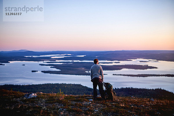 Wanderer genießt Sonnenuntergang am See  Keimiotunturi  Lappland  Finnland