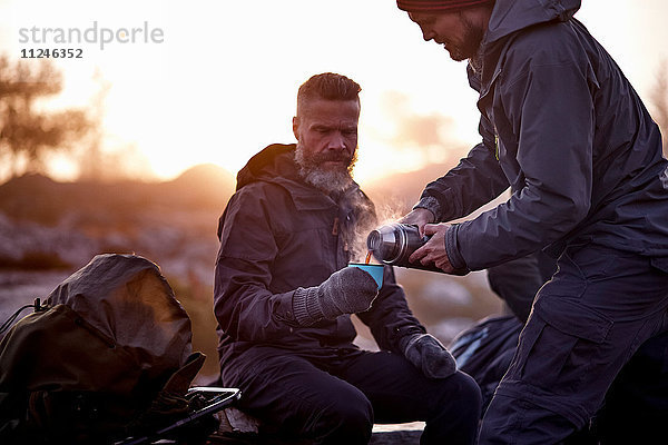 Wanderer schüttet Kaffee in die Tasse eines Freundes  Sarkitunturi  Lappland  Finnland