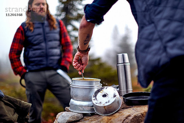 Wanderer betrachtet Freund beim Kochen  Sarkitunturi  Lappland  Finnland