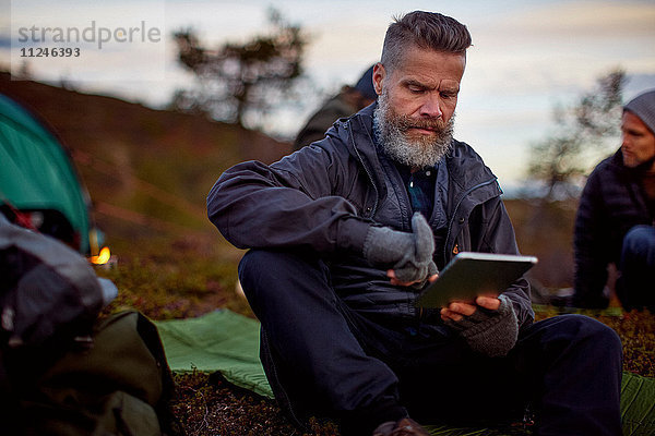 Wanderer mit digitalem Tablett im Zelt  Keimiotunturi  Lappland  Finnland