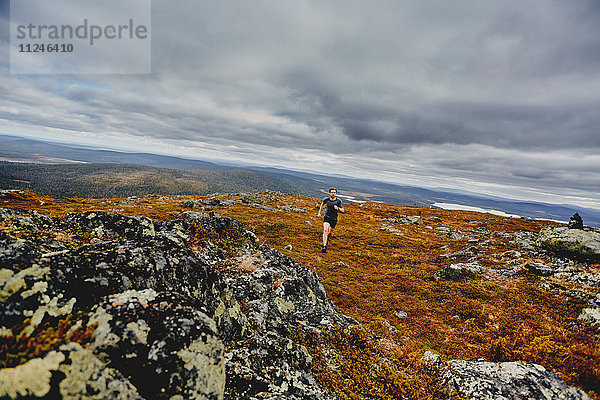 Mann läuft auf felsiger Felsspitze  Keimiotunturi  Lappland  Finnland