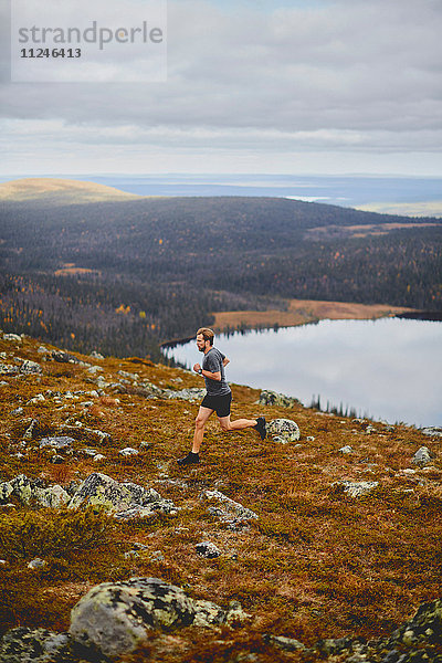 Mann läuft auf felsiger Felsspitze  Keimiotunturi  Lappland  Finnland