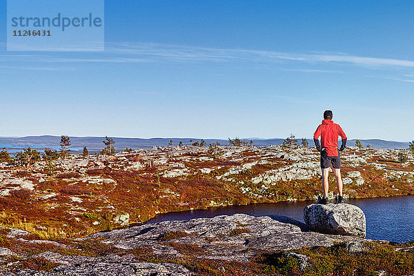 Mann mit Blick auf See auf Felsen  Sarkitunturi  Lappland  Finnland
