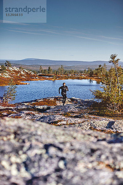 Am Ufer des Sees laufender Mann  Sarkitunturi  Lappland  Finnland