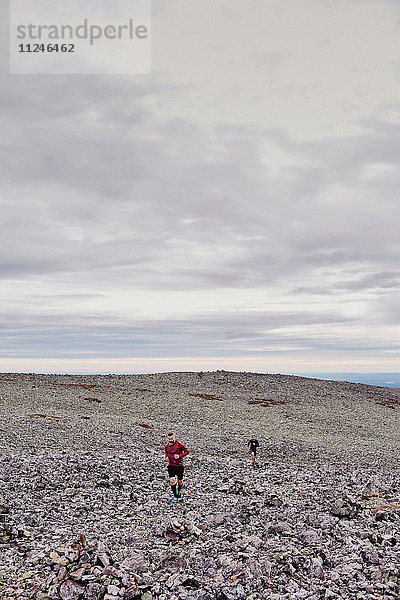 Männer laufen auf felsiger Felsspitze  Kesankitunturi  Lappland  Finnland