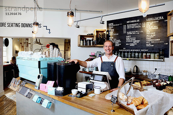 Porträt eines männlichen Geschäftsinhabers hinter der Theke eines unabhängigen Cafés