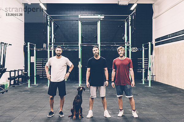 Porträt von drei männlichen Crosstrainern und Hund in Turnhalle