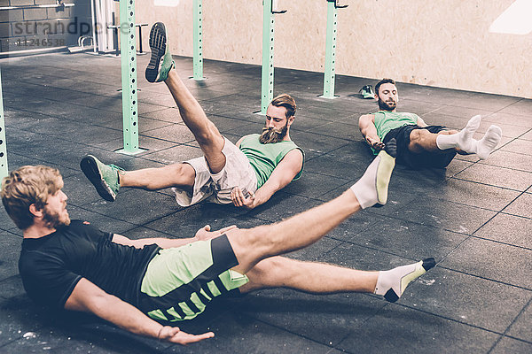 Drei männliche Crosstrainer beim Aufwärmen im Fitnessstudio