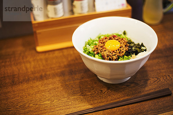 Ein Geschäft für Ramen-Nudeln. Eine weiße Nudelschüssel mit Gemüse und einem Ei.