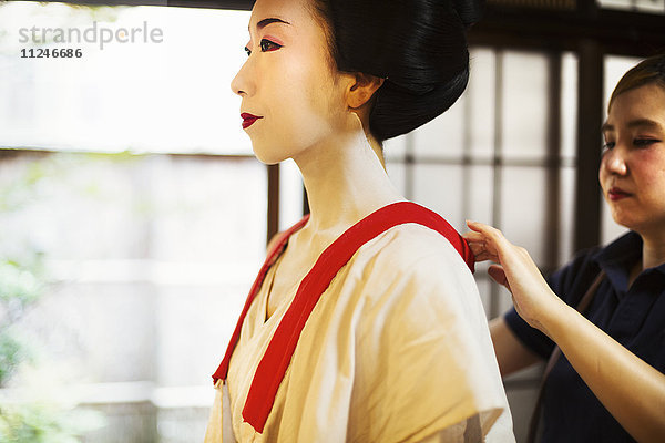 Eine moderne Geisha- oder Maiko-Frau  die in traditioneller Weise in einer weißen Schicht mit losem Kragen gekleidet ist  mit weißem Gesichtsschminke.