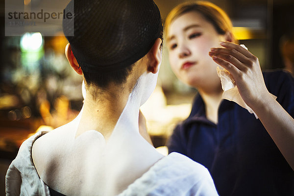 Eine moderne Geisha- oder Maiko-Frau  die nach traditioneller Art geschminkt ist  mit weißem Make-up an Hals und Schultern.