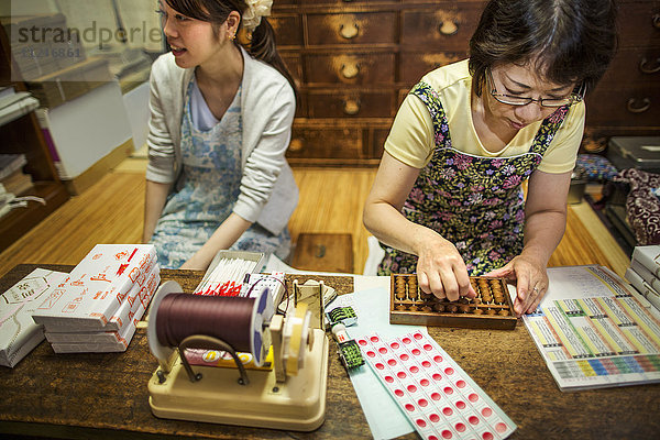 Ein kleiner handwerklicher Hersteller von speziellen Leckereien  Süßigkeiten namens Wagashi. Zwei Frauen arbeiten beim Packen von Bonbonschachteln für die Lieferung.
