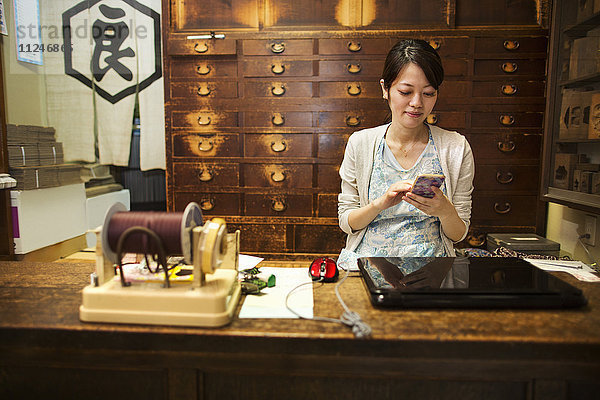 Ein traditioneller Wagashi-Süßwarenladen. Eine Frau  die an einem Schreibtisch mit Laptop und Telefon arbeitet.