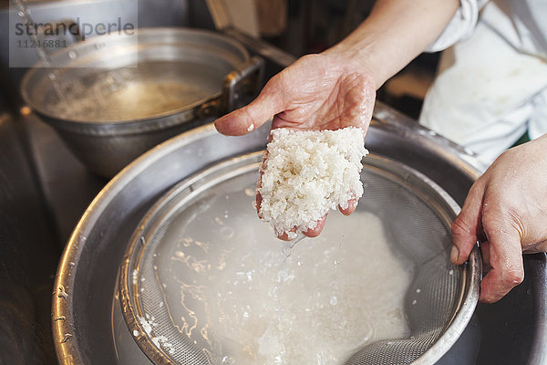 Ein Küchenchef  der in einer kleinen Großküche arbeitet  ein Itamae oder Meisterkoch  der Sushi zubereitet. Er bereitet Reis für die Gerichte vor.