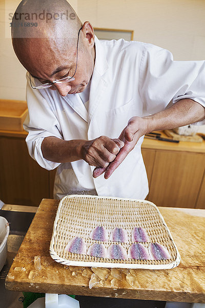 Ein Küchenchef  der in einer kleinen Großküche arbeitet  ein Itamae oder Meisterkoch  der Sushi zubereitet und Fisch zubereitet.