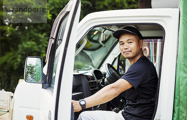 Ein junger Mann sitzt in einem Lastwagen auf einem kommerziellen Bauernhof in Japan.