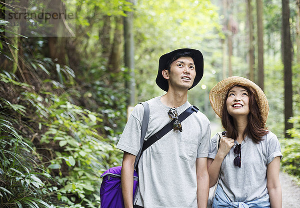 Lächelnde junge Frau und Mann stehen in einem Wald.
