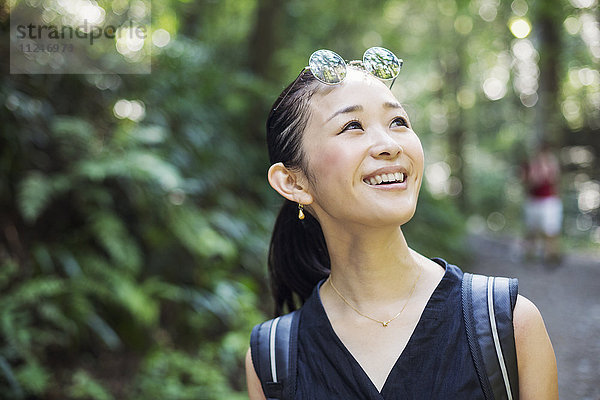 Porträt einer lächelnden jungen Frau  die in einem Wald steht.