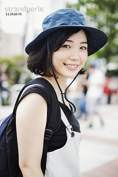 Porträt einer lächelnden jungen Frau mit Hut.