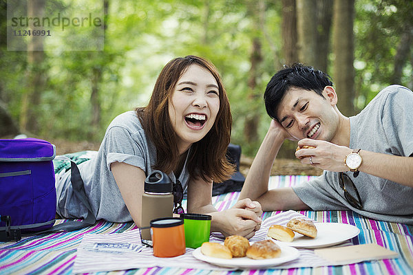 Junge Frau und Mann machen ein Picknick im Wald.