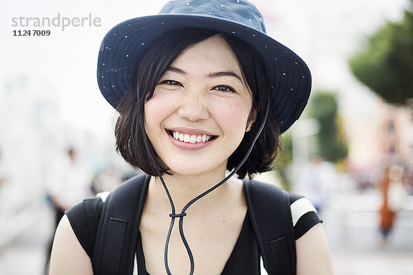 Porträt einer lächelnden jungen Frau mit Hut.