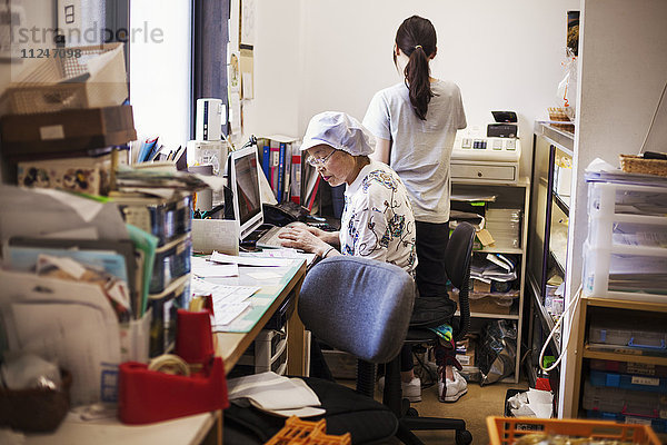 Eine reife Frau an einem Schreibtisch im Büro einer Fastfood-Einheit und Nudelproduktionsfabrik.