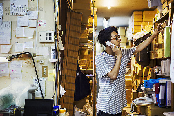 Ein Mann bei der Arbeit in der Werkstatt eines Glasmachers am Telefon.